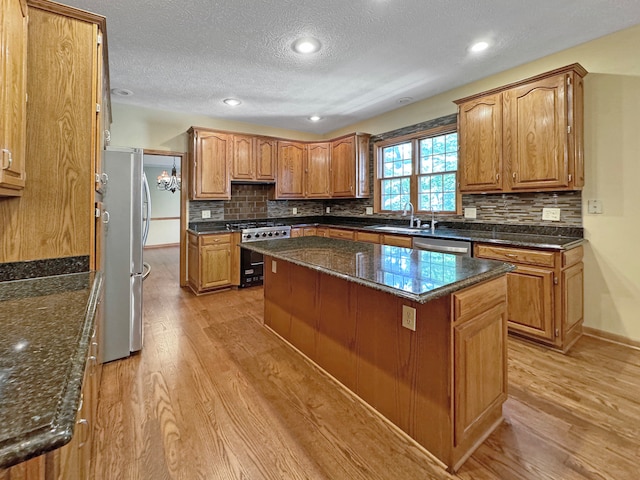 kitchen with appliances with stainless steel finishes, light hardwood / wood-style flooring, a center island, and decorative backsplash