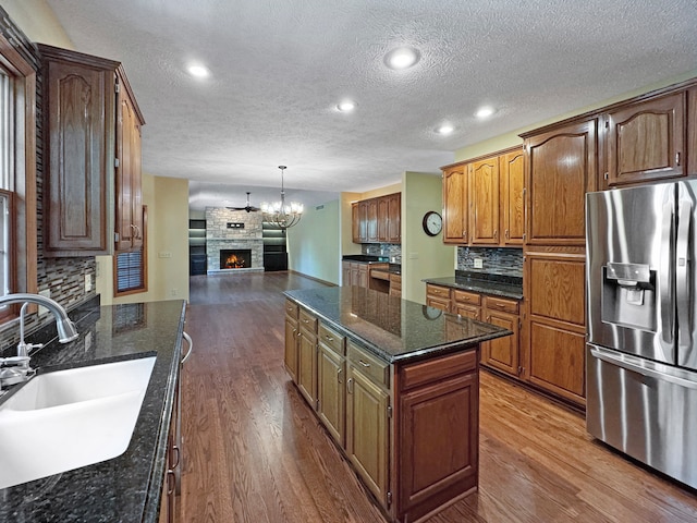 kitchen with stainless steel fridge with ice dispenser, a kitchen island, hardwood / wood-style flooring, and backsplash