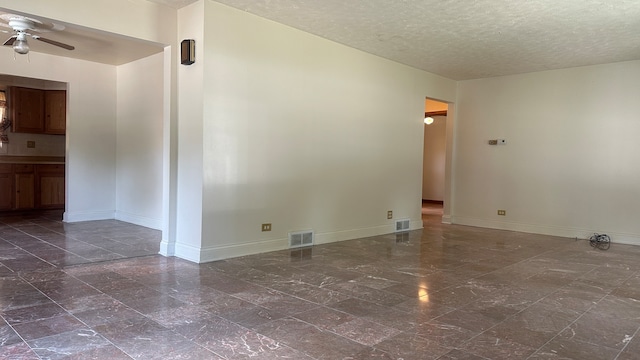 unfurnished room featuring ceiling fan, dark tile patterned floors, and a textured ceiling