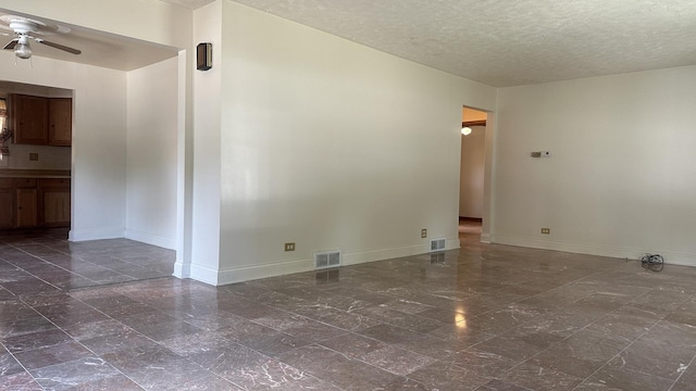 spare room featuring a ceiling fan, visible vents, a textured ceiling, and baseboards