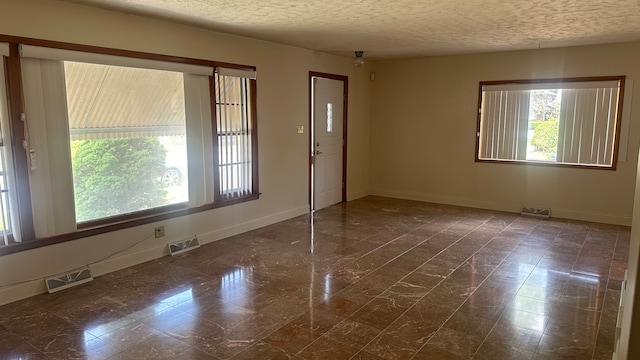 tiled spare room featuring a textured ceiling