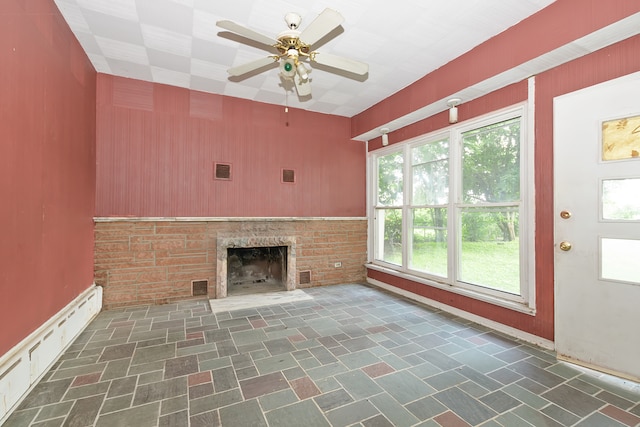 unfurnished living room with dark tile patterned floors, a healthy amount of sunlight, and ceiling fan