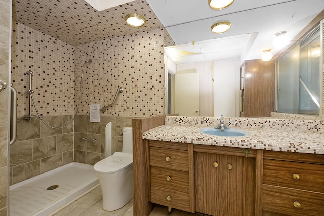 bathroom with tile walls, tiled shower, tile patterned floors, toilet, and vanity