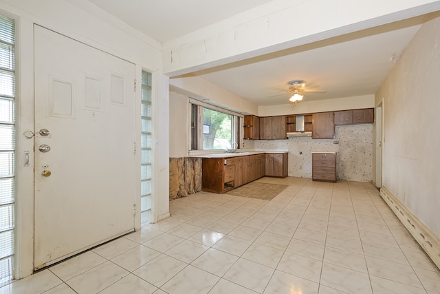 kitchen with sink, light tile patterned floors, wall chimney range hood, and ceiling fan