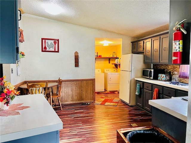 kitchen featuring vaulted ceiling, washing machine and dryer, white fridge, and a textured ceiling