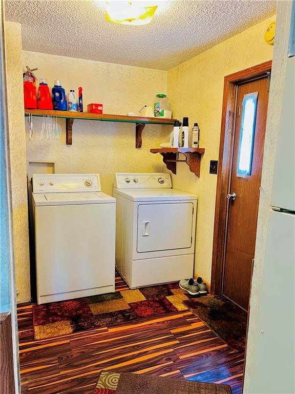 laundry room with hardwood / wood-style flooring, washer and dryer, and a textured ceiling