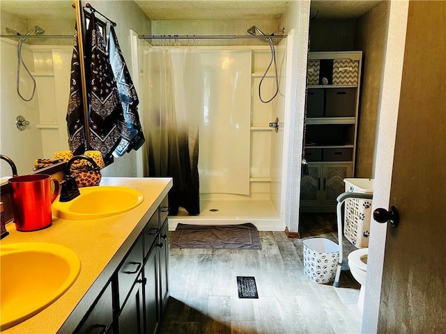 bathroom featuring hardwood / wood-style flooring, vanity, toilet, and walk in shower