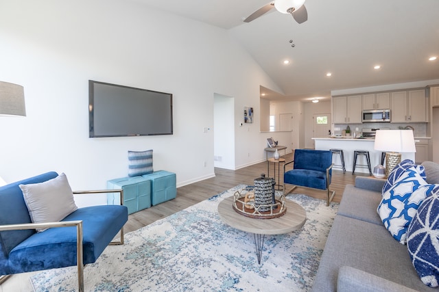 living room featuring high vaulted ceiling, light wood-type flooring, and ceiling fan