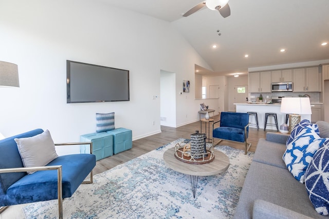 living area featuring ceiling fan, high vaulted ceiling, recessed lighting, baseboards, and light wood finished floors