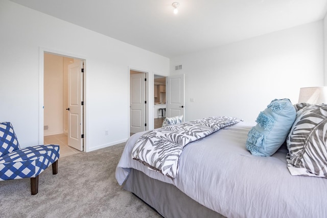 bedroom with light carpet, ensuite bathroom, visible vents, and baseboards