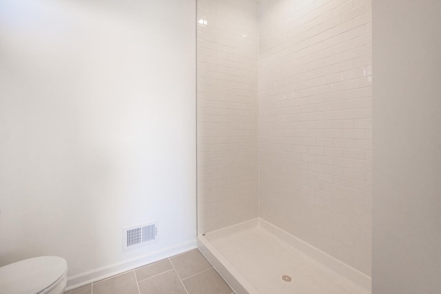 bathroom featuring baseboards, visible vents, tiled shower, toilet, and tile patterned floors