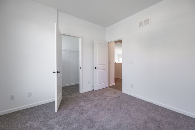 unfurnished bedroom with carpet, a closet, and a spacious closet