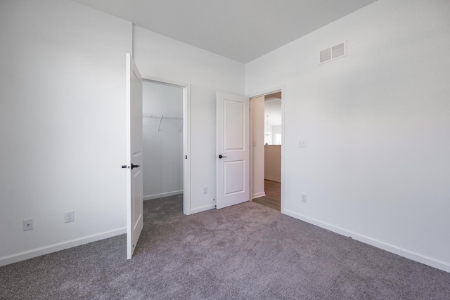 unfurnished bedroom with baseboards, visible vents, a spacious closet, carpet flooring, and a closet