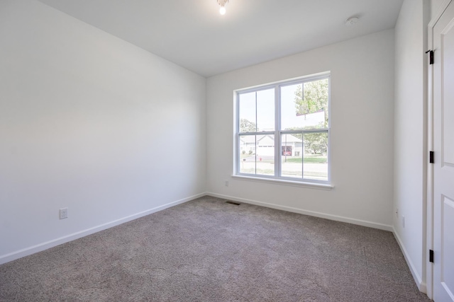 empty room with carpet floors, visible vents, and baseboards