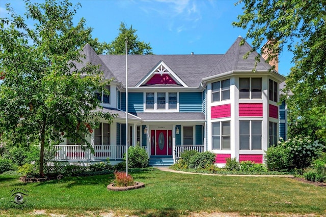 victorian house featuring a porch, roof with shingles, and a front yard