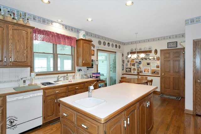 kitchen featuring a kitchen island, brown cabinets, light countertops, and white dishwasher