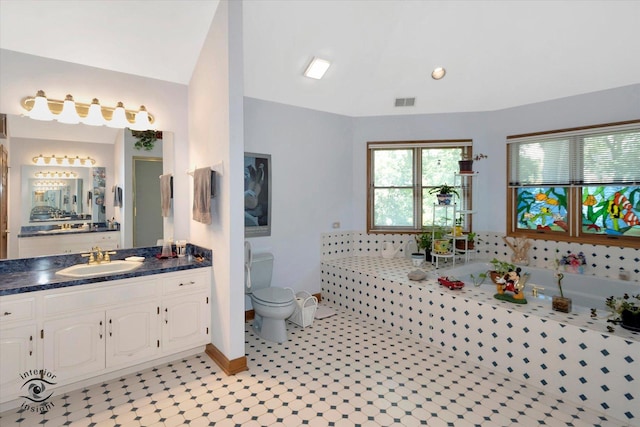 full bathroom featuring a garden tub, toilet, vaulted ceiling, vanity, and baseboards