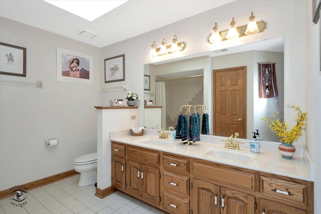 bathroom with toilet, tile patterned flooring, double vanity, and a sink