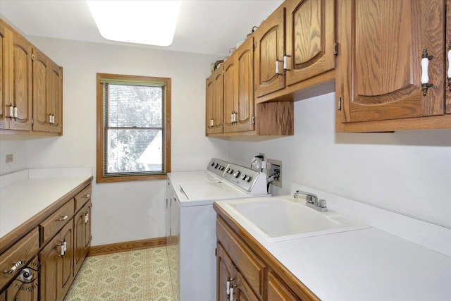 laundry room with cabinet space, a sink, baseboards, and separate washer and dryer