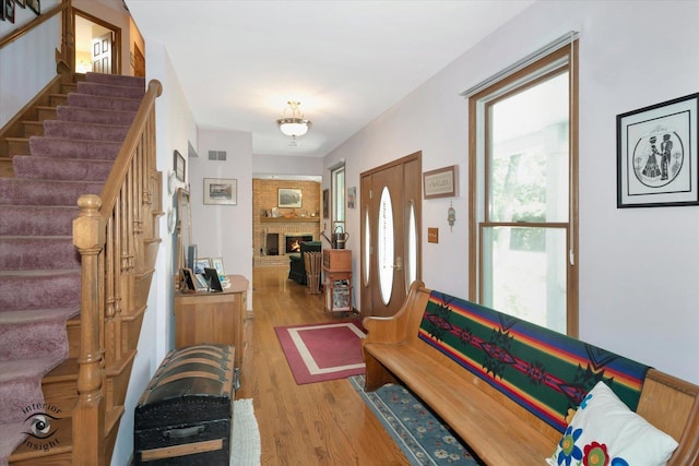 entrance foyer with visible vents, a fireplace, stairway, and wood finished floors