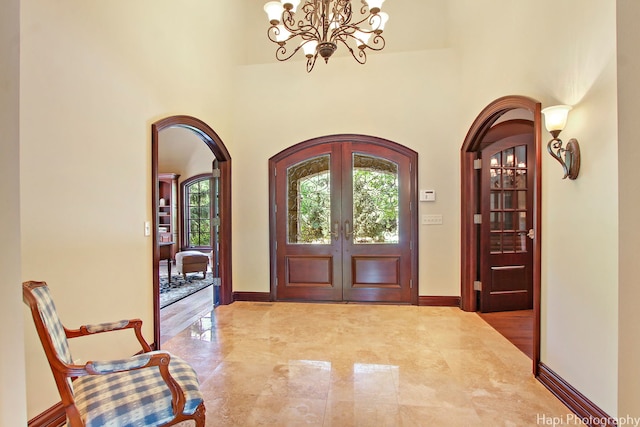 entryway with french doors, a chandelier, and a high ceiling