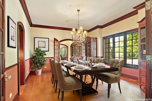 dining room featuring ornamental molding, a chandelier, and light wood-type flooring