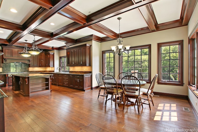 dining space featuring dark hardwood / wood-style floors, beamed ceiling, ornamental molding, coffered ceiling, and a notable chandelier