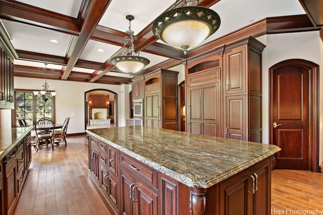 kitchen featuring coffered ceiling, pendant lighting, a center island, and beamed ceiling