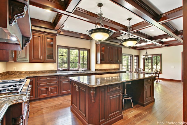 kitchen featuring dark stone countertops, decorative light fixtures, high end stove, and a center island