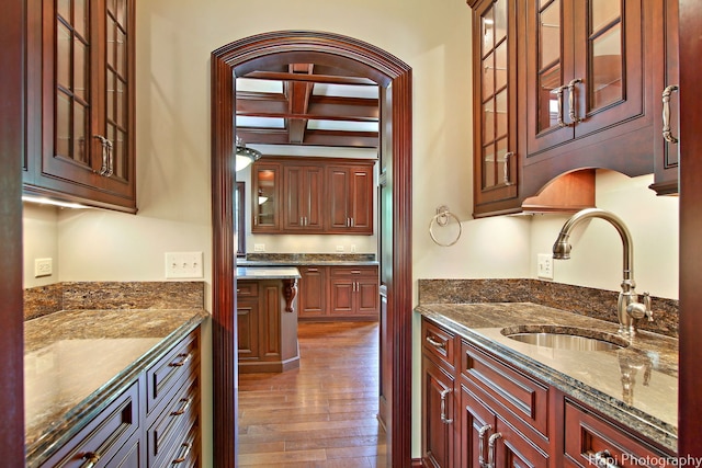 kitchen with sink, dark stone countertops, beam ceiling, coffered ceiling, and dark hardwood / wood-style flooring