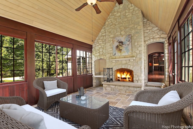 sunroom with vaulted ceiling, ceiling fan, an outdoor stone fireplace, and wood ceiling