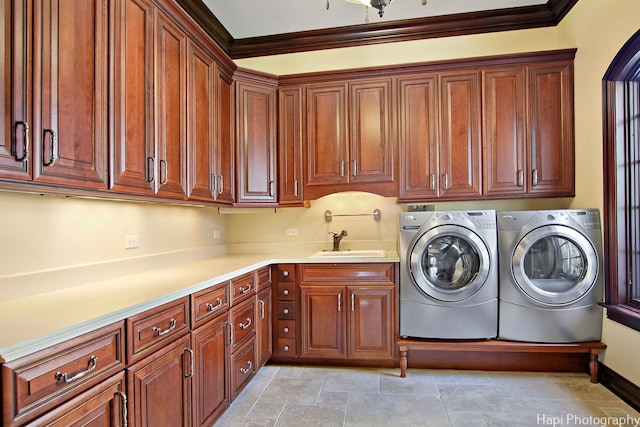 laundry room with cabinets, ornamental molding, sink, and washing machine and clothes dryer