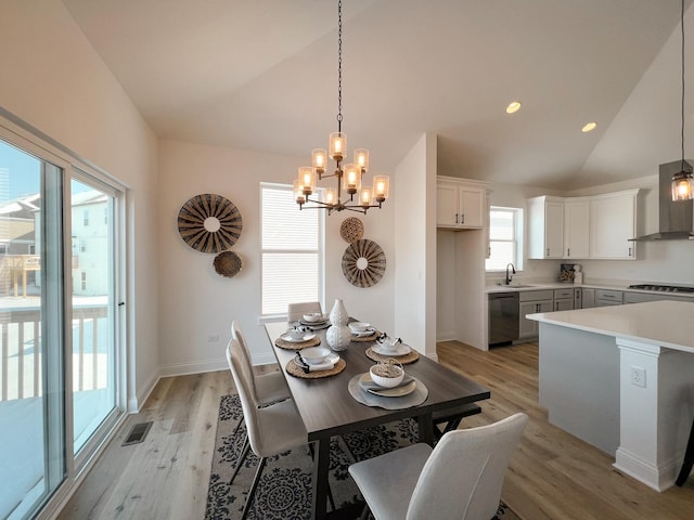 dining space featuring sink, lofted ceiling, a notable chandelier, and light hardwood / wood-style floors