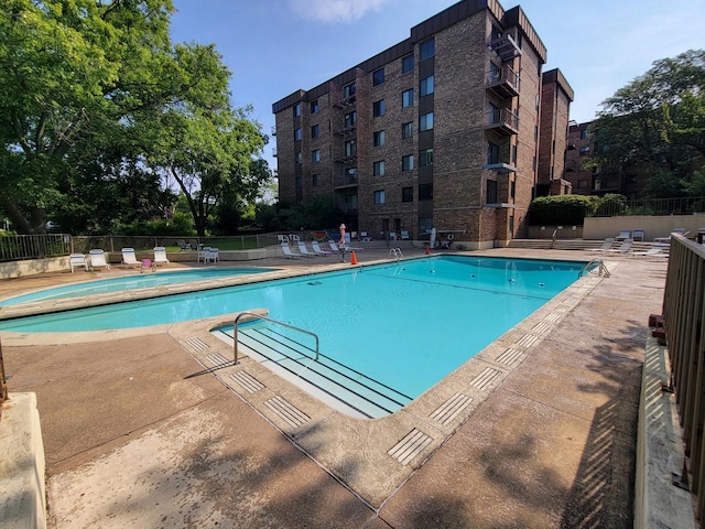 pool with a patio and fence