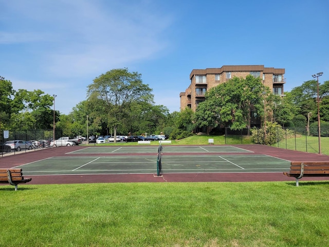 view of tennis court with fence and a lawn