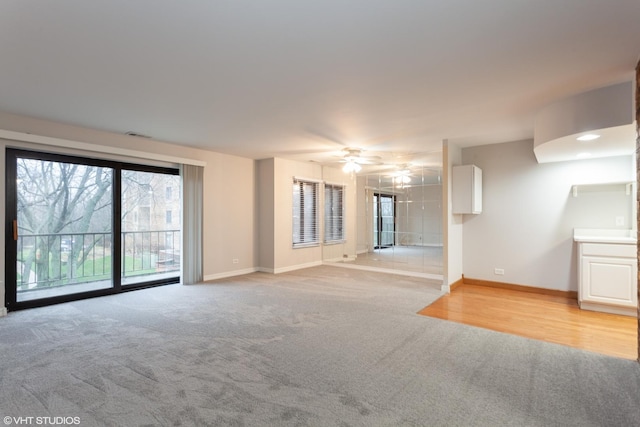 unfurnished living room with ceiling fan, baseboards, and light colored carpet