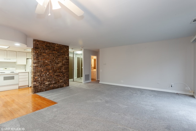 unfurnished living room with light carpet, brick wall, and ceiling fan