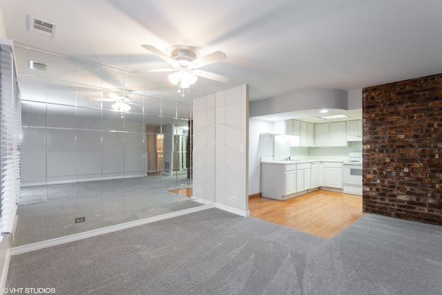 unfurnished living room featuring ceiling fan, sink, and light colored carpet