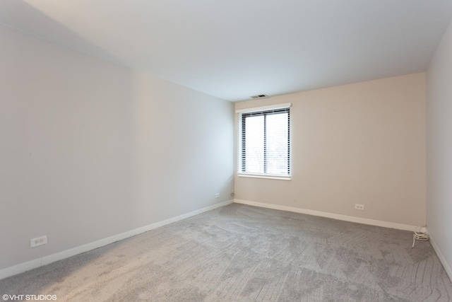 spare room featuring light carpet, visible vents, and baseboards