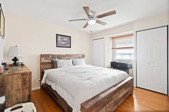 bedroom with multiple closets, wood-type flooring, and ceiling fan