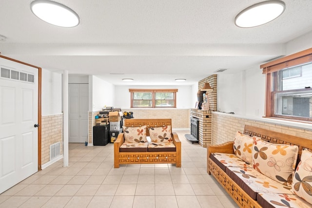 living room with light tile patterned flooring, brick wall, and a textured ceiling