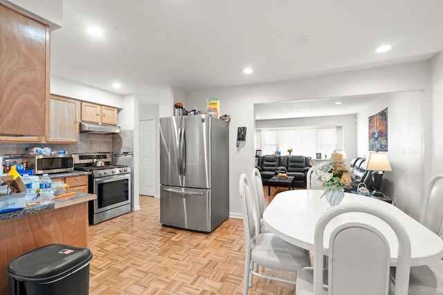 kitchen with dark stone counters, light brown cabinetry, tasteful backsplash, stainless steel appliances, and light parquet flooring