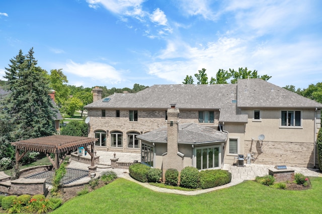 rear view of house with a patio, a chimney, a yard, a pergola, and brick siding