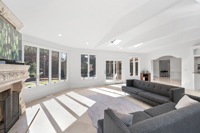 living room with lofted ceiling, arched walkways, recessed lighting, a high end fireplace, and baseboards