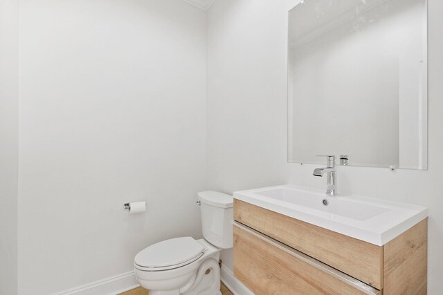 bathroom with toilet, baseboards, and vanity