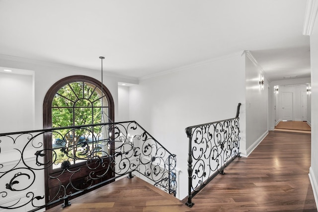 hallway with baseboards, ornamental molding, wood finished floors, and an upstairs landing