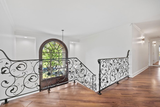 corridor with baseboards, wood finished floors, an upstairs landing, and crown molding