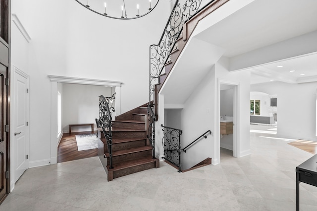 foyer entrance featuring recessed lighting, a high ceiling, an inviting chandelier, baseboards, and stairs