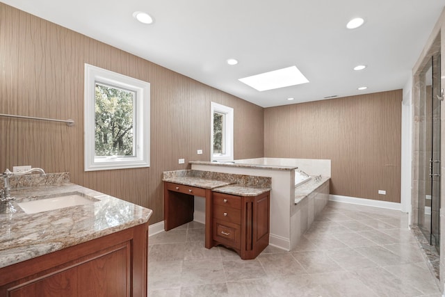 bathroom with a skylight, recessed lighting, a garden tub, and vanity