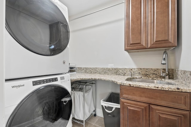 laundry area with stacked washer and clothes dryer, cabinet space, and a sink